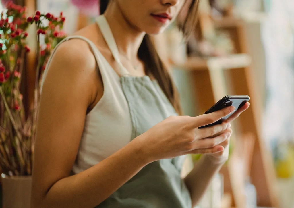お店でスマートフォンを見る、エプロン姿の店主